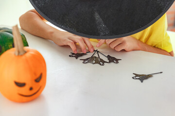Boy making jack o lantern at home white kitchen, cutting real pumpkins and playing with paper black...