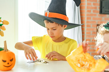 Two real siblings two brothers and sister making together jack o lantern at their home white...