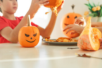 Two real happy brothers cutting together from real natural pumpkin jack o lantern, while playing...