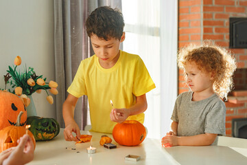 Two real happy siblings brother and sister cutting together from real natural pumpkin jack o...