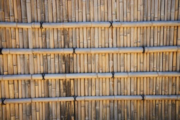 A wall made of bamboo or wooden rods. The wall is brown in color, it has a rustic feel