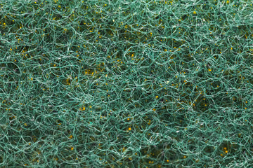 Detailed macro shot of a green scrub sponge revealing intricate texture and intertwining yellow fibers. Ideal for backgrounds, patterns, or cleaning product concepts.
