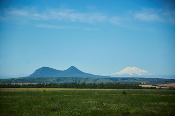 A mountain with two peaks and in the distance Mount Elbrus, the Caucasus Mountains. Comparison or similar in nature