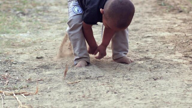 Slow motion cute baby child of Indian ethnicity standing outdoor in nature and playing with soil