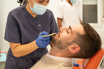 Fototapeta premium Dental technician selecting tooth shade for male patient in clinic