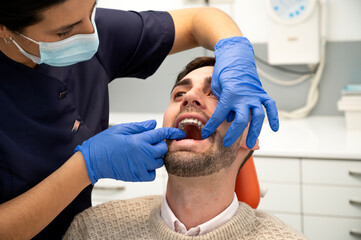 Fototapeta premium close-up of a female dentist's hands adjusting a retainer on a patient's teeth