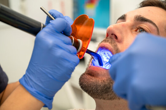 Male patient undergoing dental procedure with curing light