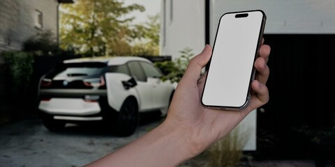 Black African-American middle aged male using smartphone with a blank white screen. Electric car, charging station, modern house apps mockup. Vertical phone orientation