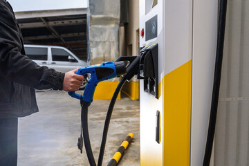 Hand Plugging Electric Car Charger into Station