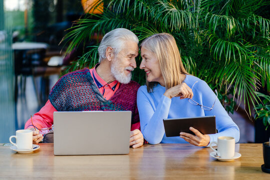 Elderly couple enjoying technology with laptops and tablets