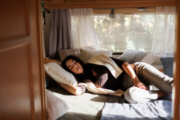 Young woman sleeping on bed in camper van in the day time