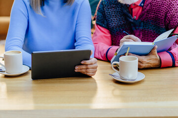 Close up of unrecognizable couple use tablet and write notes planning vacation