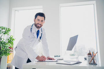 Photo of experienced doctor stand writing clipboard look in clinic center room