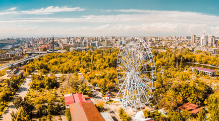 Yerevan, Armenia - 19th october, 2024: Aerial panoramic view ferris wheel in Victory Park with cityscape and buildings of Yerevan. Sunny autumn day carousels day out things to do concept