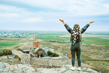 Happy tourist blogger arms up by famous Khor Virap monastery.Khor Virap is an Armenian monastery located in the Ararat Plain in Armenia. Ararat Province, within the territory of ancient Artaxata
