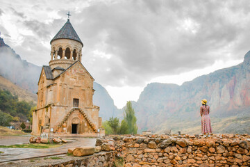 Pretty carefree Tourist woman stand on viewpoint admires view famous Armenian monastery of Noravank. Travel and tourism concept. Top popular travel explore destination caucasus