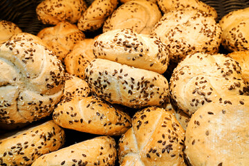 Fresh Kaiser rolls stacked on a store shelf. Group of classic bread rolls on display. Pile of golden brown buns with sesame seeds. Perfect for sandwiches or breakfast. Crisp, freshly baked roll.