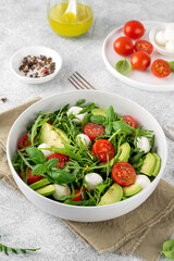 Fresh salad with arugula, mozzarella, tomatoes and avocado in a bowl. Healthy vegetarian dish.