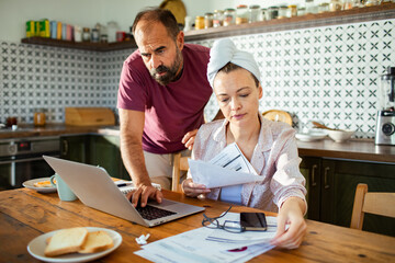 Obraz premium Couple reviewing bills and finances together at kitchen table