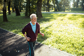 Senior man jogging in park on a sunny day for exercise and fitness
