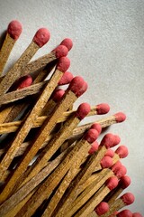  Close-up of several old matchsticks with red tips and sticks scattered across a smooth granite surface.