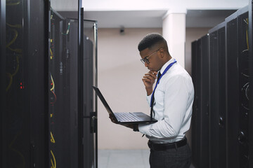 Black man, technician and thinking with laptop in server room for software, hardware or network...