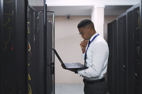 Black man, technician and thinking with laptop in server room for software, hardware or network repair. Male person, IT engineer or wonder with computer for fix, technical service or system backup