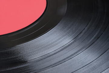 Close-up vinyl record, retro music. Black vinyl record with red label.