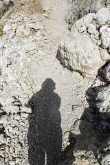 hikers shadow on a rocky mountain trail during a hot summer day