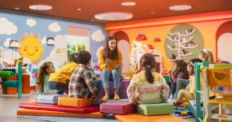 Beautiful Daycare Teacher Learning Alphabet with Young Talented Kids. Female Educator Supervising...