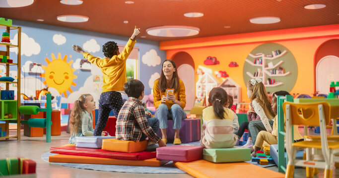 Cheerful Daycare Teacher Using Gaming and Acting Methods to Teach Multiethnic Kids Alphabet in Kindergarten. Small Cute Boys and Girls Getting Basic Reading and Writing Skills, Learning Alphabet