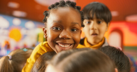 Portrait of an Adorable Stylish Black Girl Posing, Looking at Camera and Smiling. Cheerful African Child Spending Productive Time in Daycare, Playing Alone with Colorful Building Blocks