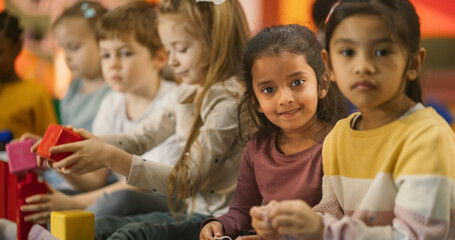 Portrait of a Group of Diverse Kids Playing with Colorful Building Blocks in Daycare Center. Cute Little Creative Girls Focused on Making a Magical Toy House. Childhood and Kindergarten Concept