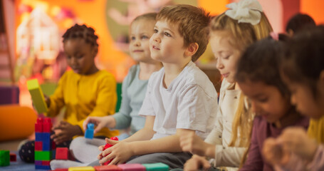 Cute Caucasian, Asian and African Kids Playing Together with Colorful Building Blocks. Smart Adorable Children Spend Time in Kindergarten, Develop Their Physical and Social Skills