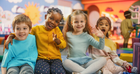 Portrait of Happy Diverse Children Sitting on a Floor and Posing Together in a Modern Kindergarten. Beautiful International Small Kids Looking at Camera, Smiling