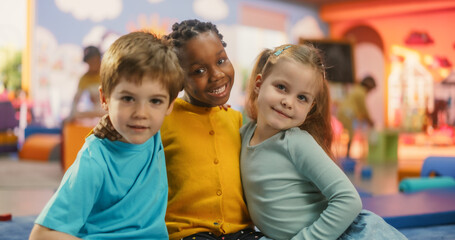 Portrait of Happy Diverse Children Sitting on a Floor and Posing Together in a Modern Kindergarten....