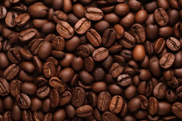 A close-up background filled with roasted coffee beans, showcasing their rich, dark brown color and glossy texture on warm-toned background