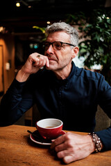 Pensive senior man drinking coffee and thinking in cafe