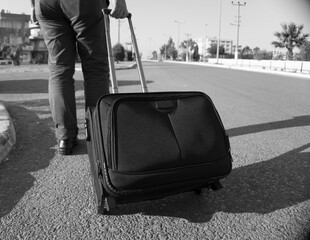 A black and white image of a man pulling luggage on a road, representing travel or the journey of life.