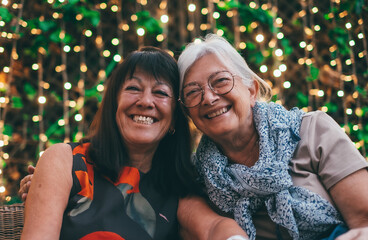 Cheerful couple of senior women enjoying their friendship posing smiling for a photograph. Two affectionate mature women looking at the camera