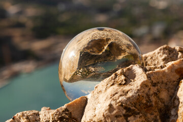Obraz premium Crystal glass ball sphere reveals nature landscape with macro view