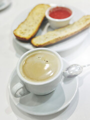 A white cup of espresso coffee and toasted bread with fresh tomato pasta for breakfast are on the table. Vertical image. Traditional Spanish breakfast.