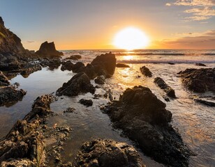 Obraz premium Rocky Beach With Jagged Black Rocks and Shimmering Tide Pools Reflecting the Colors of the Setting Sun, With Waves Gently Crashing on the Shore in the Distance