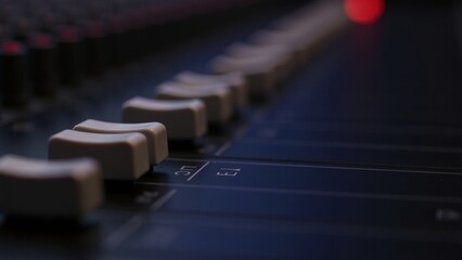 A detailed view of knobs and sliders on an audio mixing console, showcasing the intricate controls used during music production in a recording studio