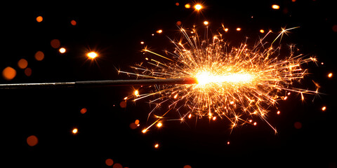 Fototapeta premium Sparkler Igniting with Bright Sparks Against Dark Background