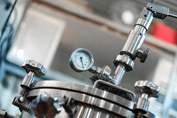 A close-up of a pressure gauge attached to a metal tank in a manufacturing facility