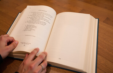 Fototapeta premium Open book on wooden table with hand resting on page in warm light