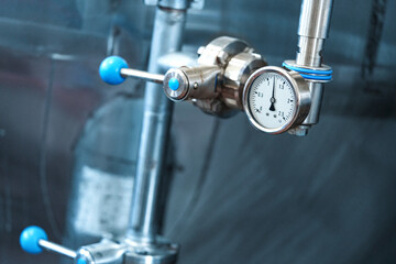 A close-up of a pressure gauge mounted on a pipe in an industrial setting