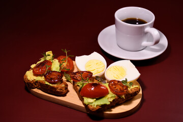 Healthy breakfast. toast with avocado paste and fried tomatoes, boiled egg. Cup of coffee on a saucer.