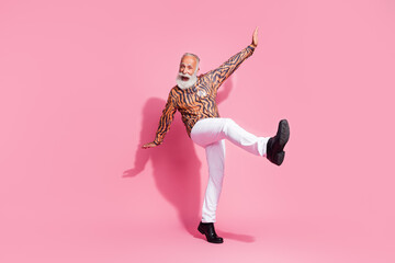 Photo of positive excited old man raise hands dancing moving have fun wear shiny clothes isolated pink color background